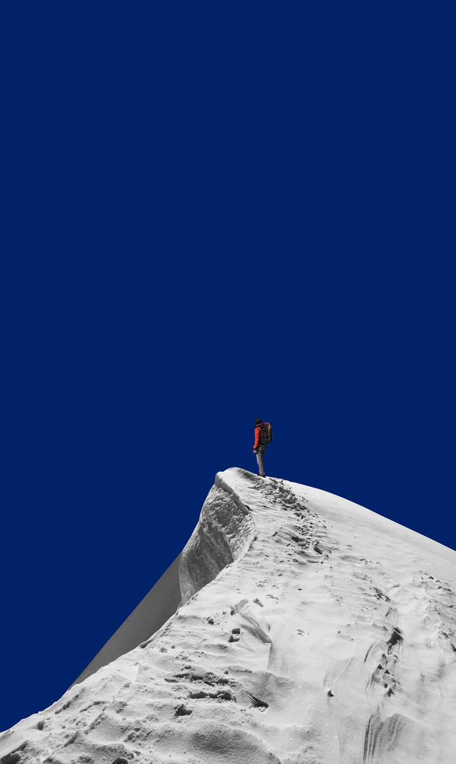 A man on a mountain summit stands proudly, capturing a moment of victory and exploration.