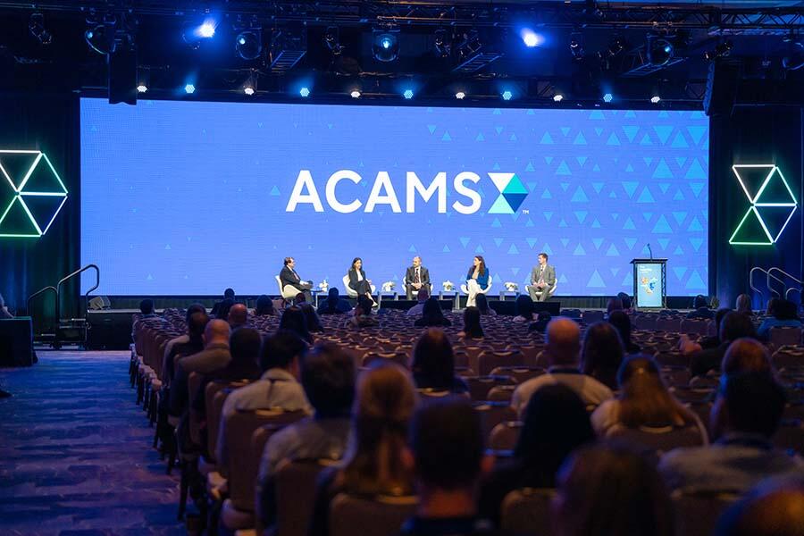Acams conference attendees engaged in discussions and networking at a professional event.
