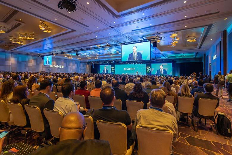A large crowd of attendees gathered in a conference room, engaged in discussions and networking activities.