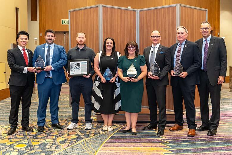 A group of professionals in business attire proudly holding their awards, celebrating their achievements together.