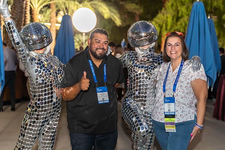 Two individuals pose with silver disco dancers at a lively event, capturing a moment of celebration and fun.