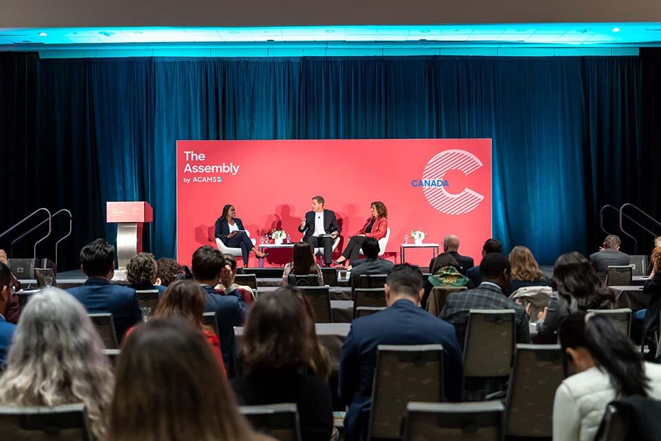 A diverse group of individuals seated in chairs, attentively participating in a conference setting.