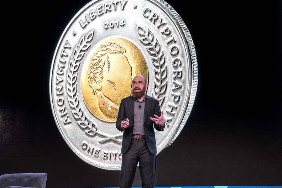 ACAMS Hollywood expert speaking on stage in front of a large coin